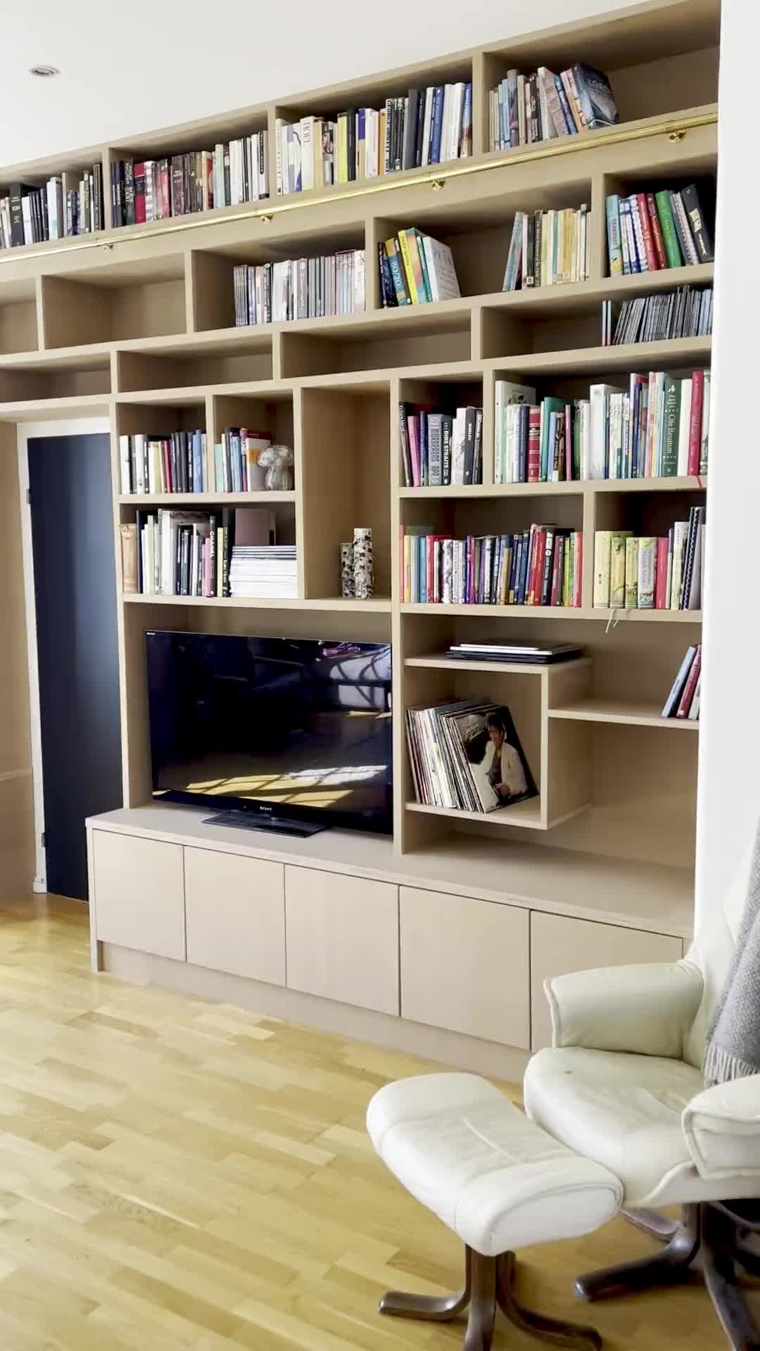 Biblioteksstigen i heltre eik hektet på messingrøret foran hylla.