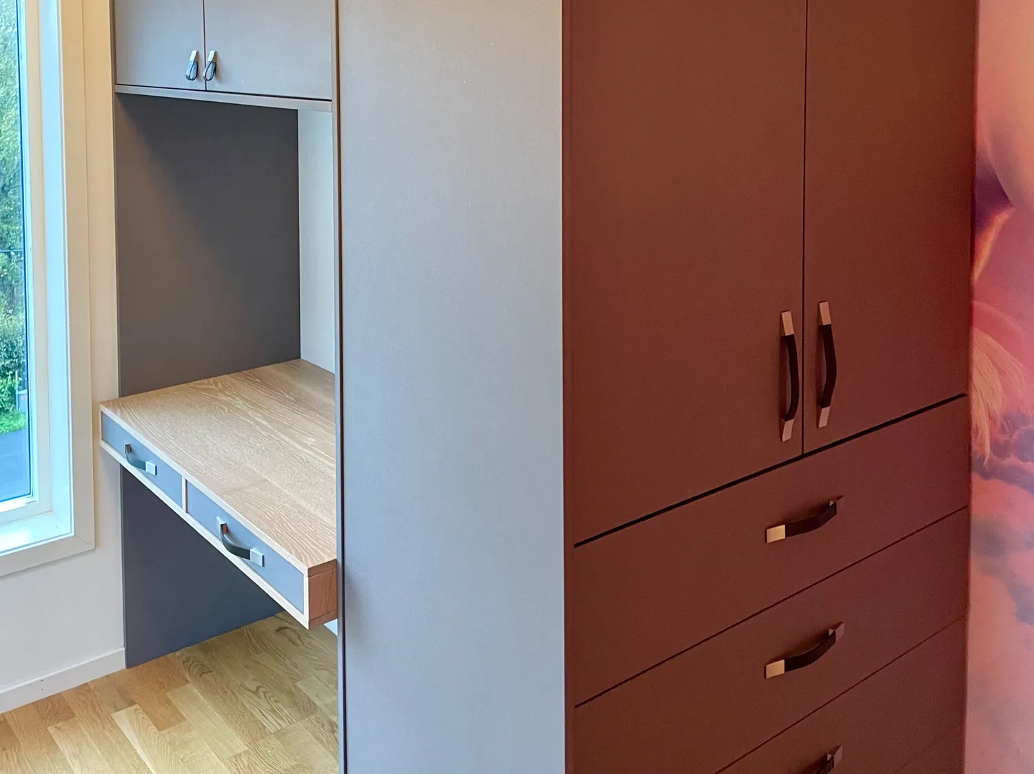 Innebygd garderobe med skrivebordsnisje på et barnerom, sett på skrå i hjørnet.