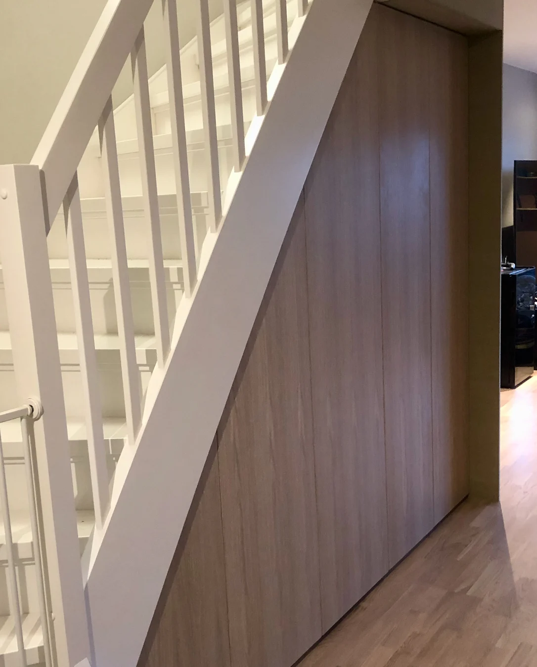 Garderobe under trapp med fronter i eik.